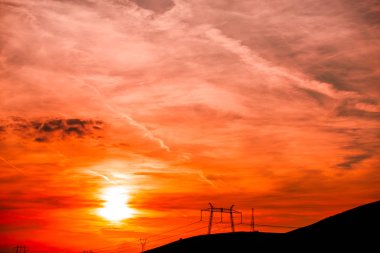 Elektrik direkleri ve gün batımı gökyüzü arka plan ile Alan