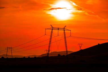 Elektrik direkleri ve gün batımı gökyüzü arka plan ile Alan