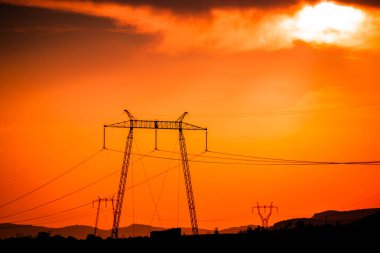 Elektrik direkleri ve günbatımı gökyüzü parlak manzara