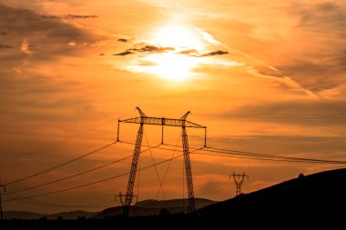 Elektrik direkleri ve gün batımı gökyüzü arka plan ile Alan