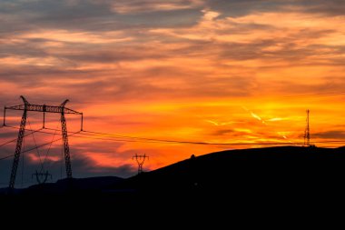 Elektrik direkleri ve gün batımı gökyüzü arka plan ile Alan