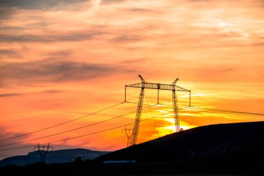 Turuncu günbatımı gökyüzü arka plan ile elektrik direkleri 