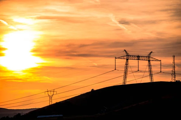 Electric poles with orange sunset sky background