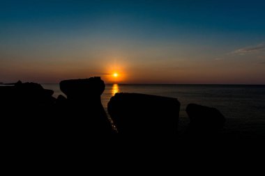 Dalgakıran bloklarla deniz günbatımı gökyüzü turuncu güneşte