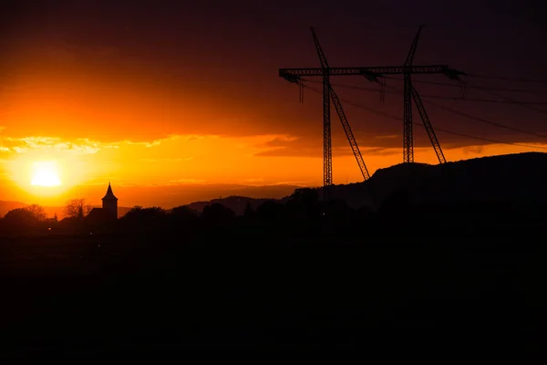 带电线杆和日落天空背景的田野 — 图库照片