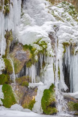 donmuş şelale buz sarkıtları ve kayalık dağ üzerinde yeşil yosun