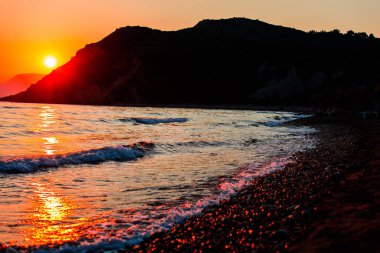 akşam günbatımı gökyüzü, dağlar ve su dalgalar deniz