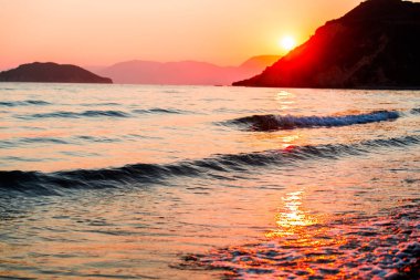 Deniz suyu ve dağlar yukarıda gökyüzü günbatımı 