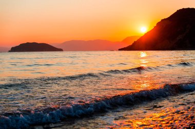 akşam günbatımı gökyüzü, dağlar ve su dalgalar deniz