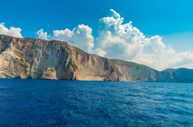 kayalık sahil ve deniz su, mavi gökyüzü beyaz bulutlar ile 
