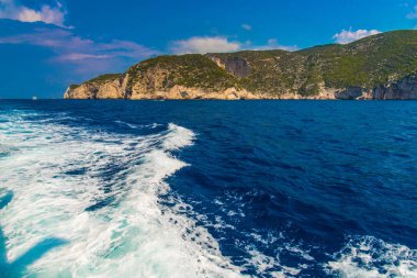 kayalık sahil ve deniz su, mavi gökyüzü beyaz bulutlar ile 