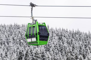 Karlı orman arka plan ile turistik yeşil teleferik