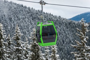 Karlı orman arka plan ile turistik yeşil teleferik