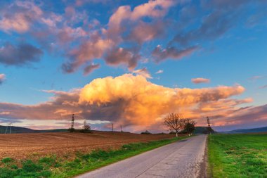 Yol, elektrik direkleri ve gün batımı gökyüzü arka plan ile Alan
