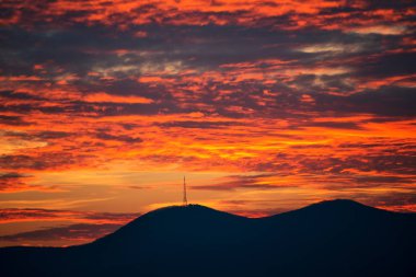görkemli kırmızı günbatımı gökyüzü ve tepeler siluet ufuk üzerinde  