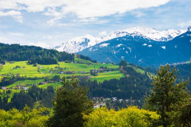 Arka planda evleri ve dağları olan yeşil alanlar
