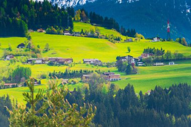 Arka planda evleri ve dağları olan yeşil alanlar