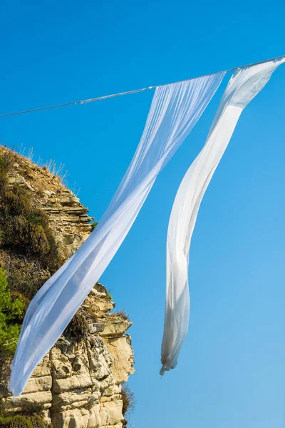 White waving curtains drying on thread line on natural background