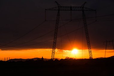 Bulutlu gün batımı gökyüzü ve elektrik direkleri