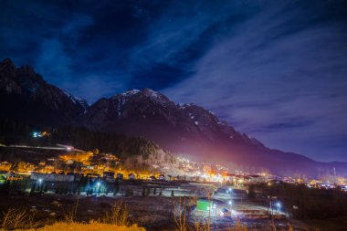 gece gökyüzünde yıldız Dağları ve ışıklı küçük bir köy evlerinde yukarıda 
