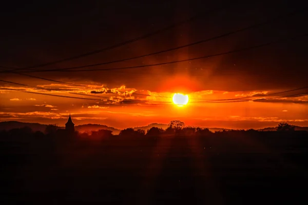 Leuchtend Orangefarbener Sonnenuntergang Auf Feld Mit Strommasten — Stockfoto