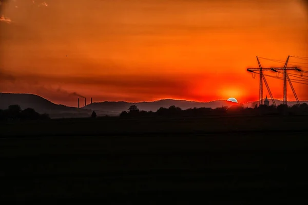 Leuchtend Orangefarbener Sonnenuntergang Auf Feld Mit Strommasten — Stockfoto
