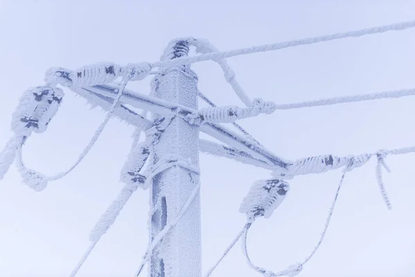 电线杆与电缆覆盖着雪在天空背景 — 图库照片