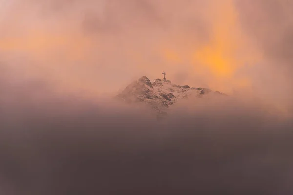 Облака Живописных Альпийских Горах Оранжевое Небо Заката Религиозный Крест Вершине — стоковое фото