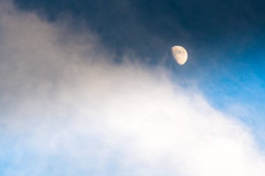 Bulutlar arasında parlak ay ile koyu mavi gökyüzü