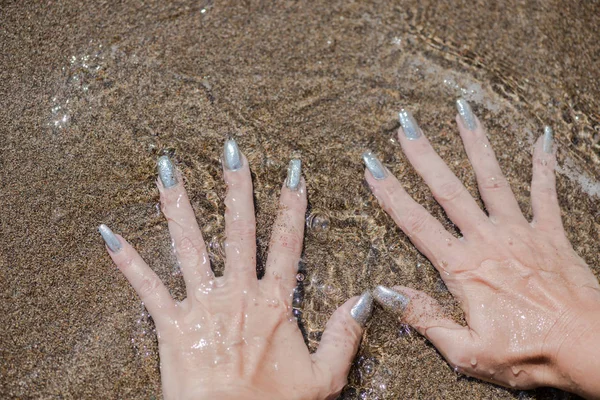 Vrouwelijke Handen Met Zilveren Nagellak Kust Achtergrond — Stockfoto