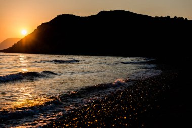 akşam günbatımı gökyüzü, dağlar ve su dalgalar deniz