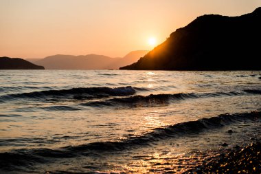 turuncu günbatımı gökyüzü güneş, dağlar ve deniz su yüzeyi ile akşam