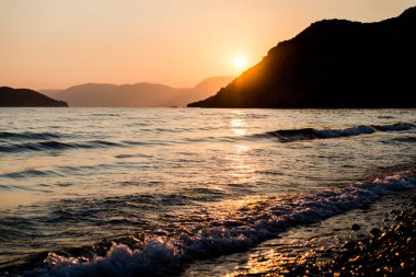 turuncu günbatımı gökyüzü güneş, dağlar ve deniz su yüzeyi ile akşam