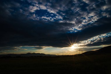 Çayır alacakaranlıkta, günbatımı arka plan karanlık gökyüzü ile 