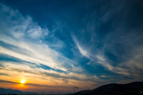 夕暮れの草原 カラフルな空とふわふわの雲に夕日を背景 — ストック写真