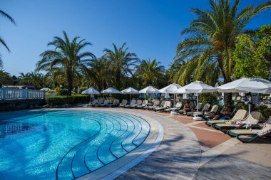 Havuz kenarındaki şezlonglarda dinlenen turistler