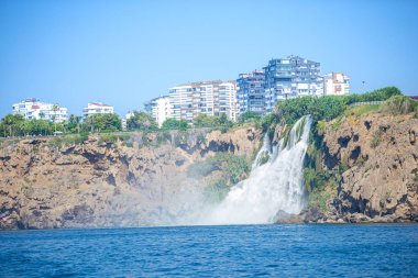 Arka planda kayalık kayalık ve Türk binaları ile deniz manzarası