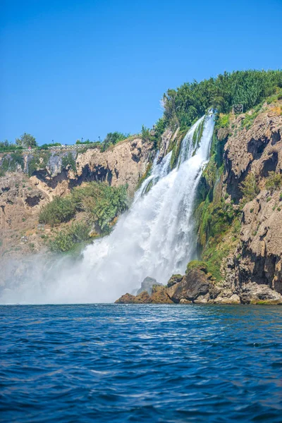 Rocky cliff with waterfall by black sea