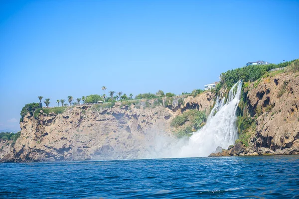 Rocky cliff with waterfall by black sea