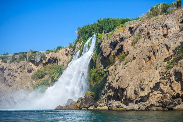 Rocky cliff with waterfall by black sea