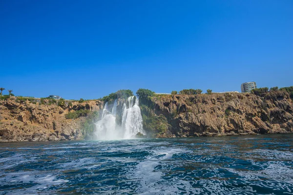 Rocky cliff with waterfall by black sea