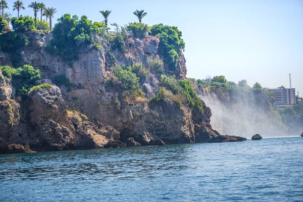 Rocky cliff with waterfall by black sea