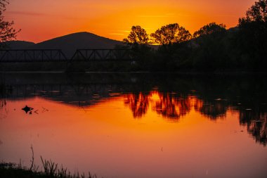 Gün batımında tepeleri olan nehir, doğal arka plan.