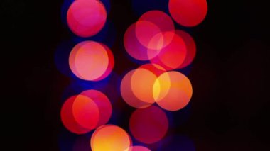 Siyah arka planda çok renkli yanıp sönen bir bokeh. Yeni yılın parlak çelenklerinin renkli ışıkları