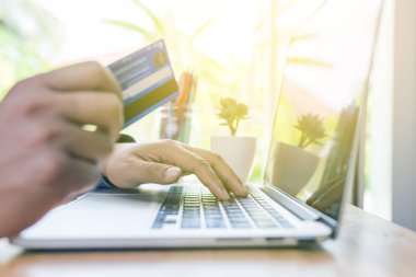 adam ahşap masa oturan ve o için kredi kartı ile dizüstü bilgisayar kullanarak