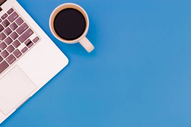 mavi masa üzerinde dizüstü bilgisayar ile modern işyeri düz yatıyordu Ofis masası masa, üst görünüm dizüstü arka plan ve siyah arka plan üzerinde kopya alanı, dizüstü bilgisayar ile mavi masa ofis, akıllı telefon ve kahve fincan ile diğer iş malzemeleri.