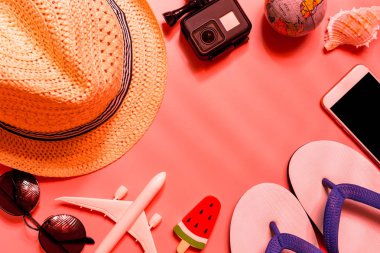 Metin için boş alan ile pembe arka planda gezgin aksesuarları, tropikal palmiye yaprağı ve uçak üst görünümü.