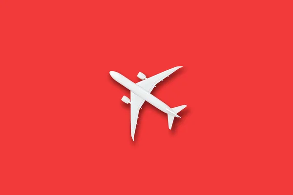 Model white plane, airplane on red color background with copy space, Flat lay design travel concept on red background. top view model air plane on red color background.