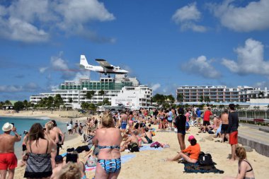 St Martin, Dutch Antelles - December 25, 2018: Airplanes land low over Maho Beach, St martin. the destination is a major tourist attraction of the island. clipart