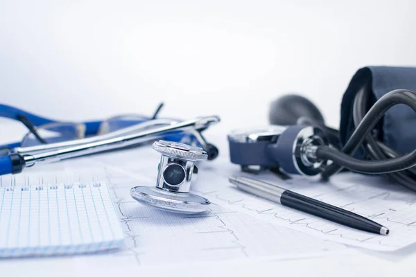 Stetoskop na stole roboczym kardiologa. Tonometr, EKG i Notatnik z kitel, medyczną koncepcję — Zdjęcie stockowe